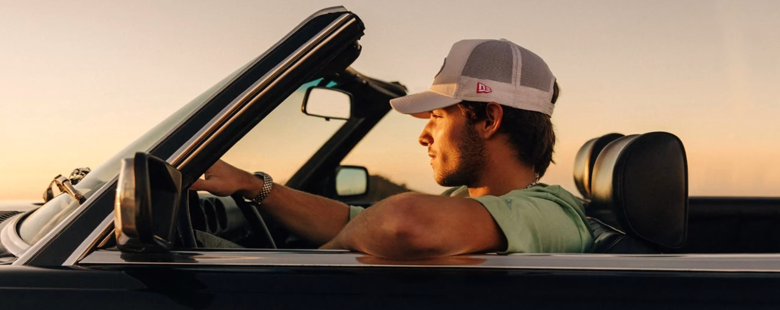 New Era model wearing cap in a car